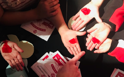 People around a table holding small red cellophane fish that react to heat in their hands. We developed Psychic fish to stimulate conversations about how fish feel. 